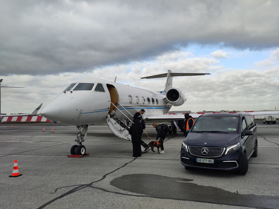 Gulfstream jet on runway beside Mercedes Benz van