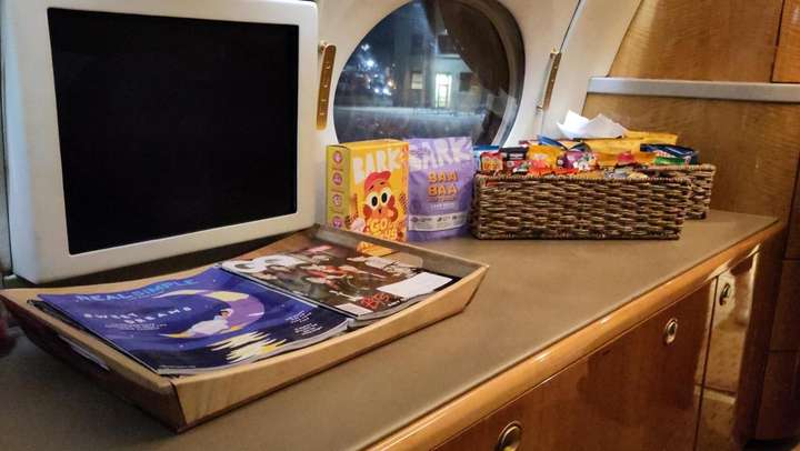 TV Screen, Magazines, dog and human snacks on airplane cabinet